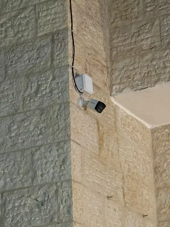 كاميرا مراقبة صغيرة مركّبة على زاوية جدار خارجي مع صندوق توصيلات